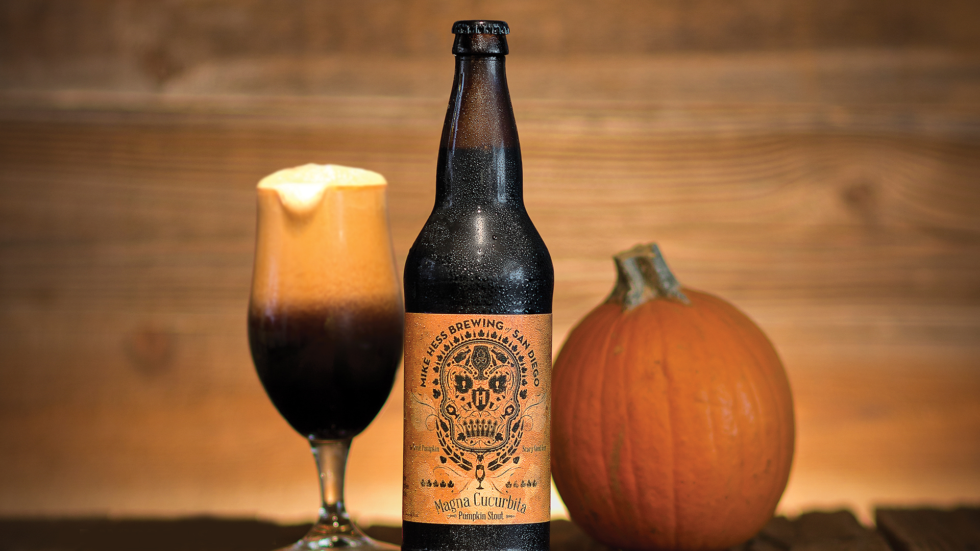 1920x1080-magna-beer-bottle Photograph of a glass of stout, next to a beer bottle and a pumpkin